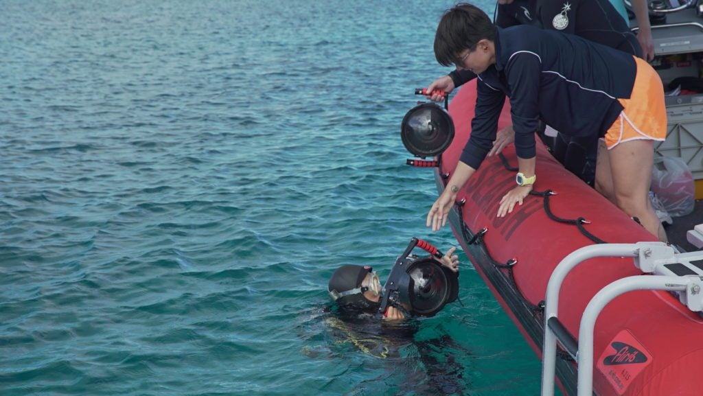 Stacy Peltier, Bermuda Institute of Ocean Sciences (BIOS), hands an underwater camera to Yvonne Sawall, also from BIOS. Credit: Jim Round/NASA JPL